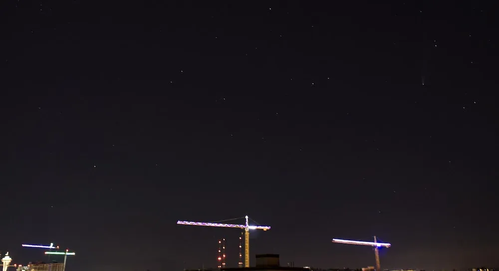 Comet NEOWISE as a faint streak in the night sky above the Seattle skyline.